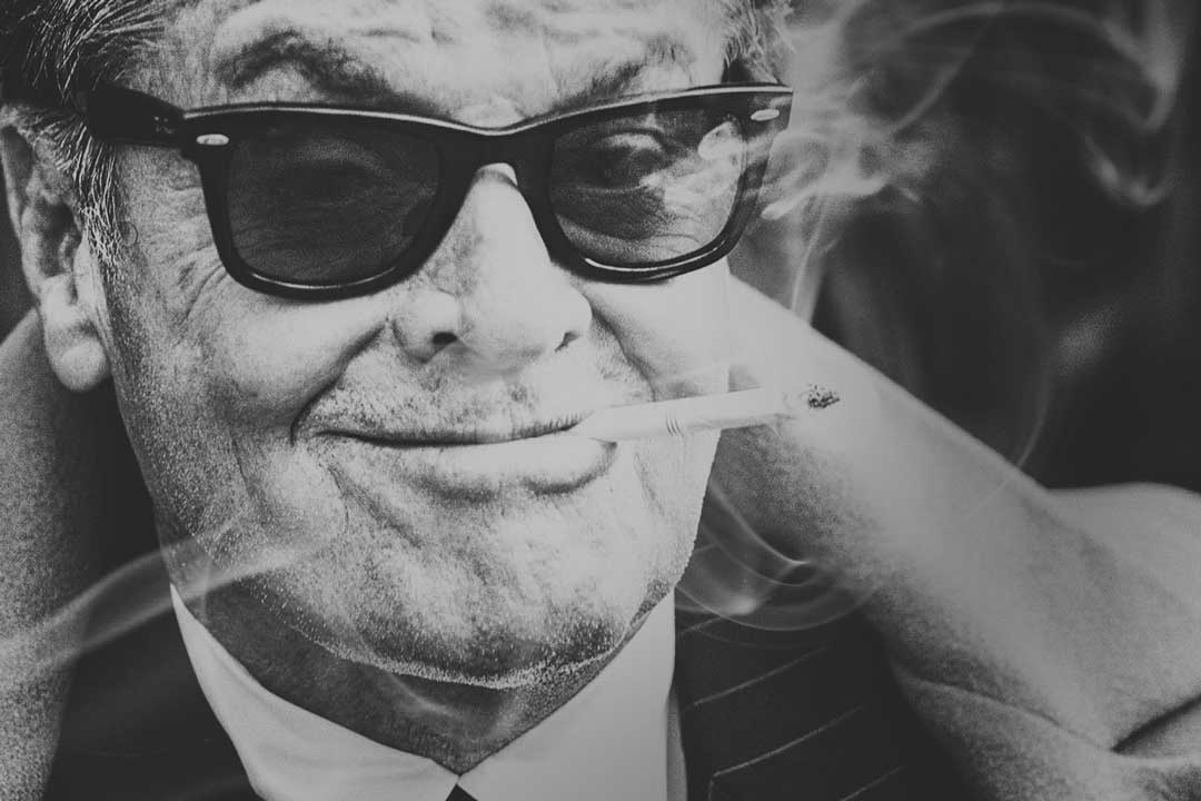 Jack Nicholson wearing black RayBan Wayfarer sunglasses with a cigarette in his mouth