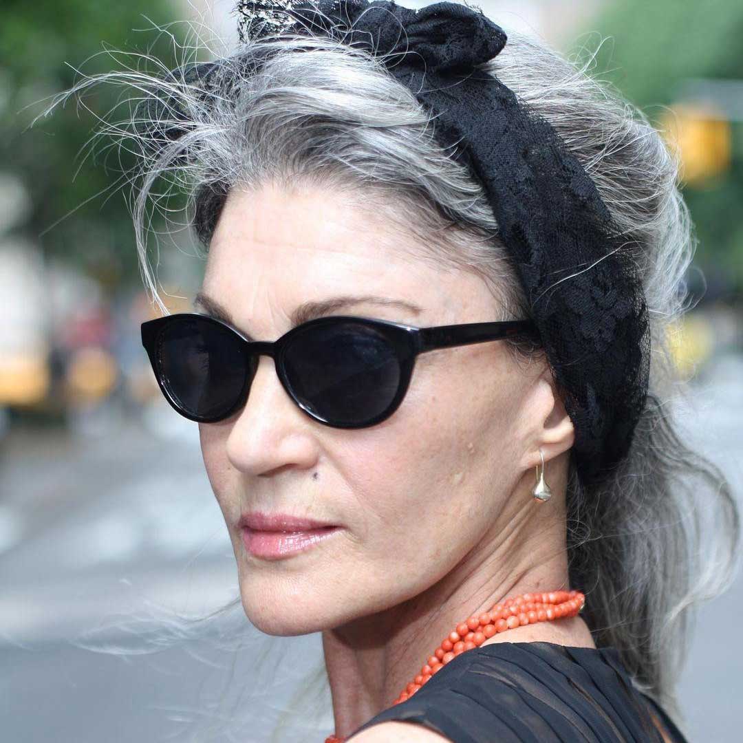 Lady wearing dark sunglasses with her long grey hair tied up with black crochet hairband