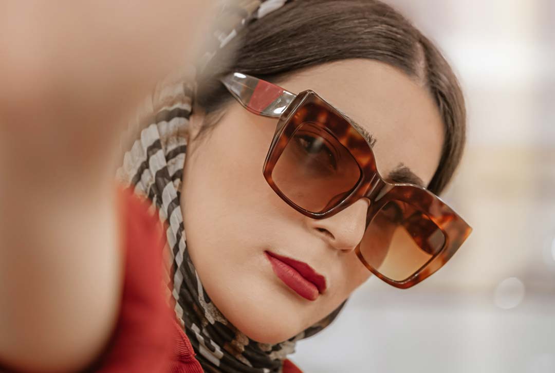 Lady wearing large oversized tortoise sunglasses frame with brown lenses