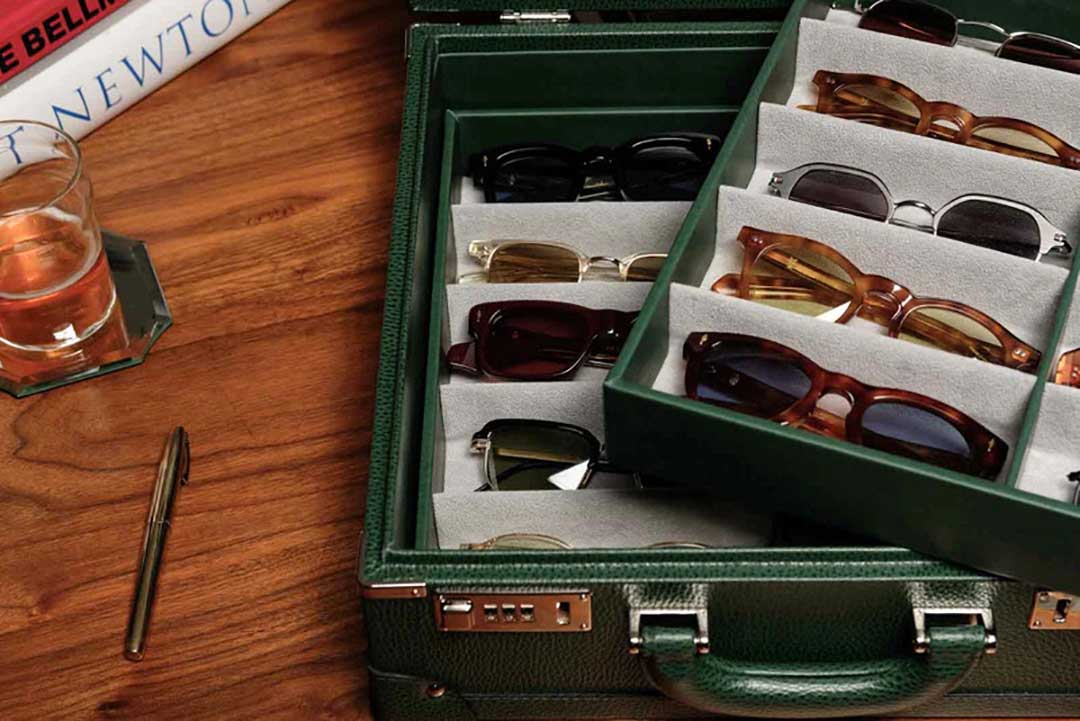 Large green leather sunglasses box lying on wood table