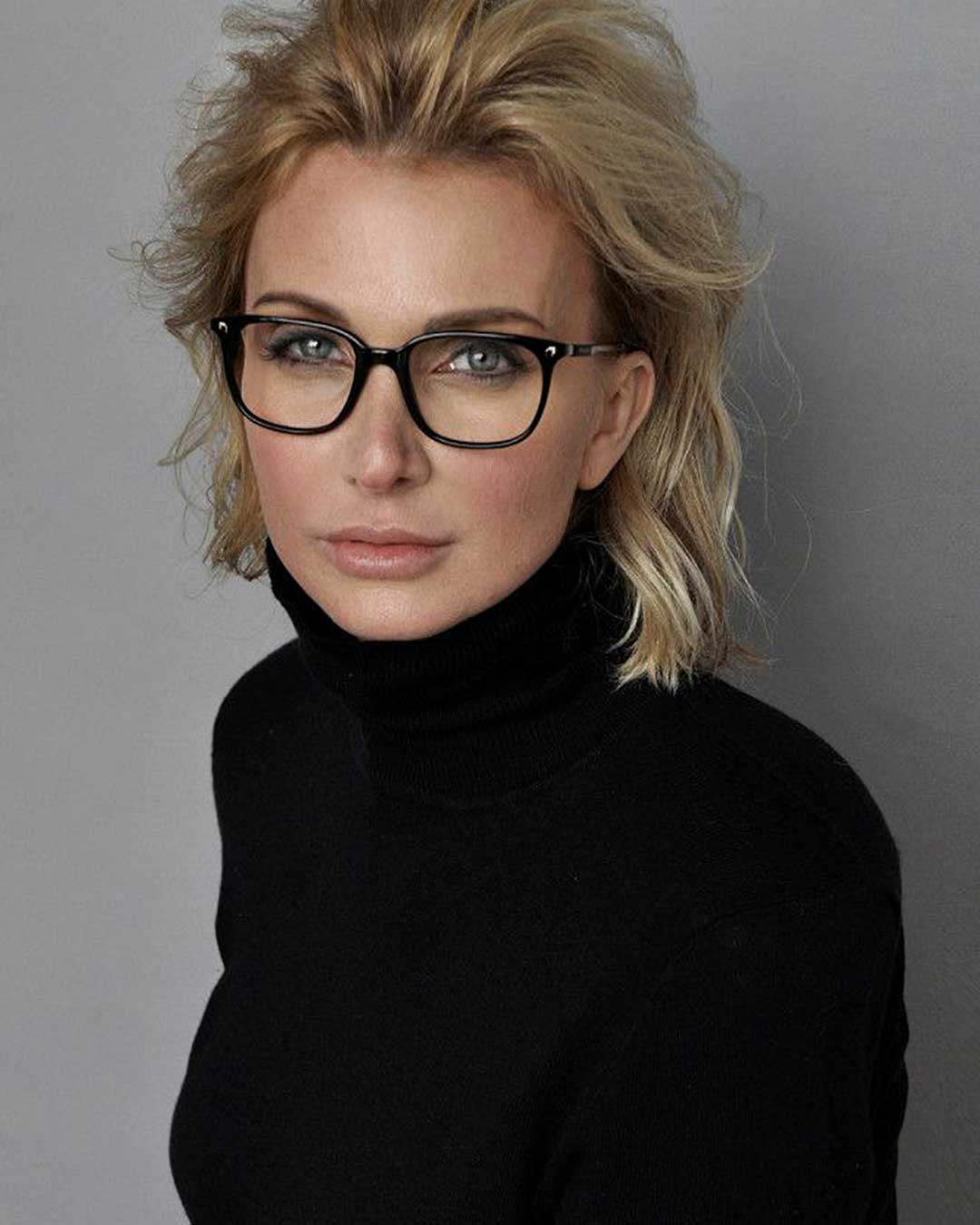 Light haired woman wearing black roll neck sweater and square black eyeglasses frame