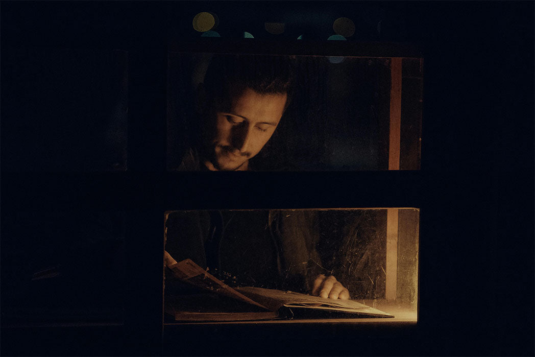 Man reading book at a table in a very dark room