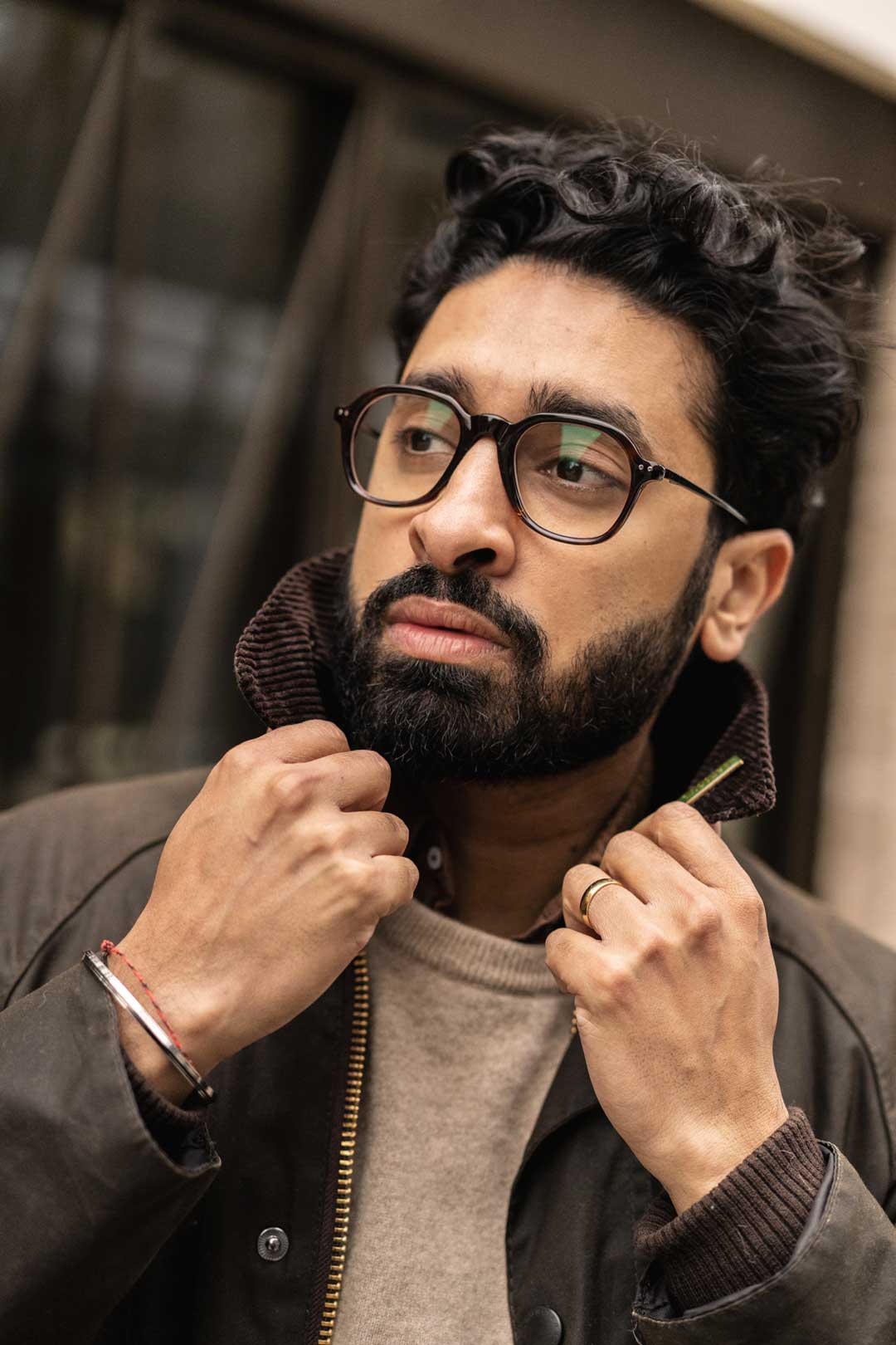 Man adjusting his jacket collar in street waring vintage style eyeglasses frame