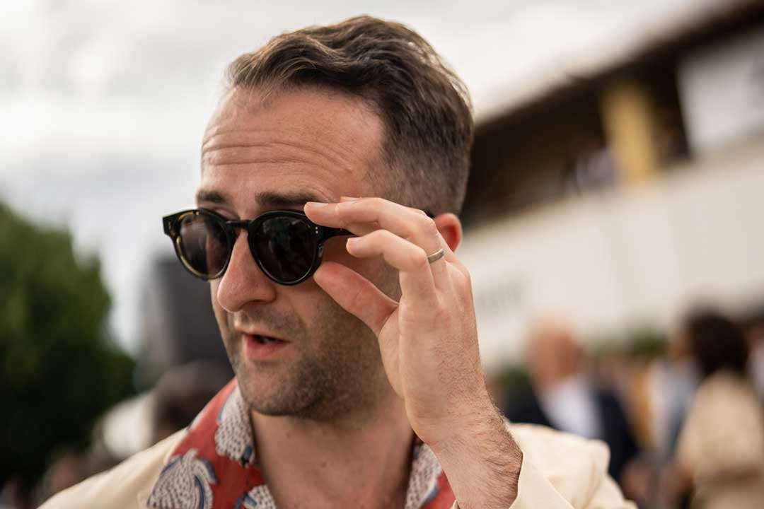 Man adjusting the position of his round sunglasses frame with one hand