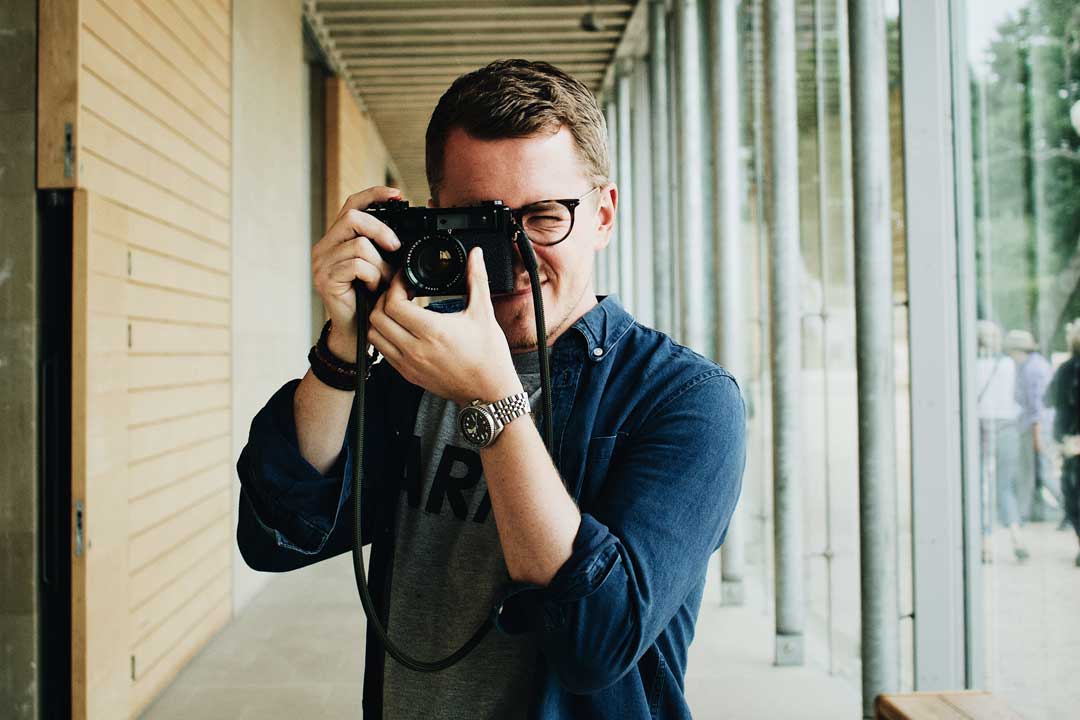 Man looking taking a photograph wearing eyeglasses and blue shirt