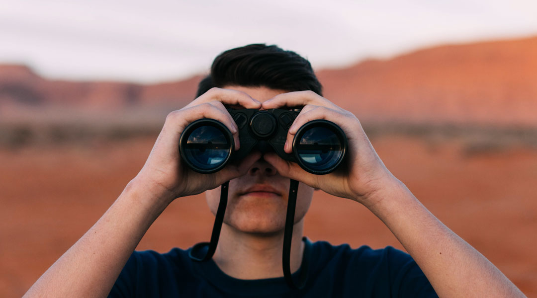 Man using a pair of black binoculars