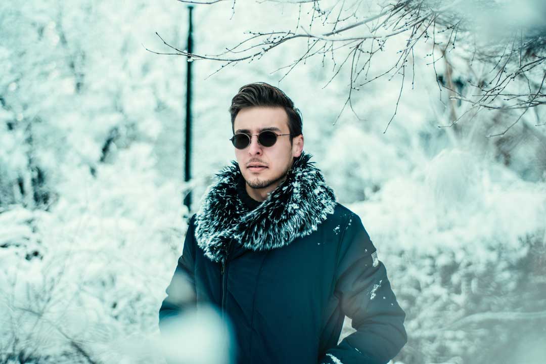 Man wearing fur lined coat and sunglasses frame on a snowy day