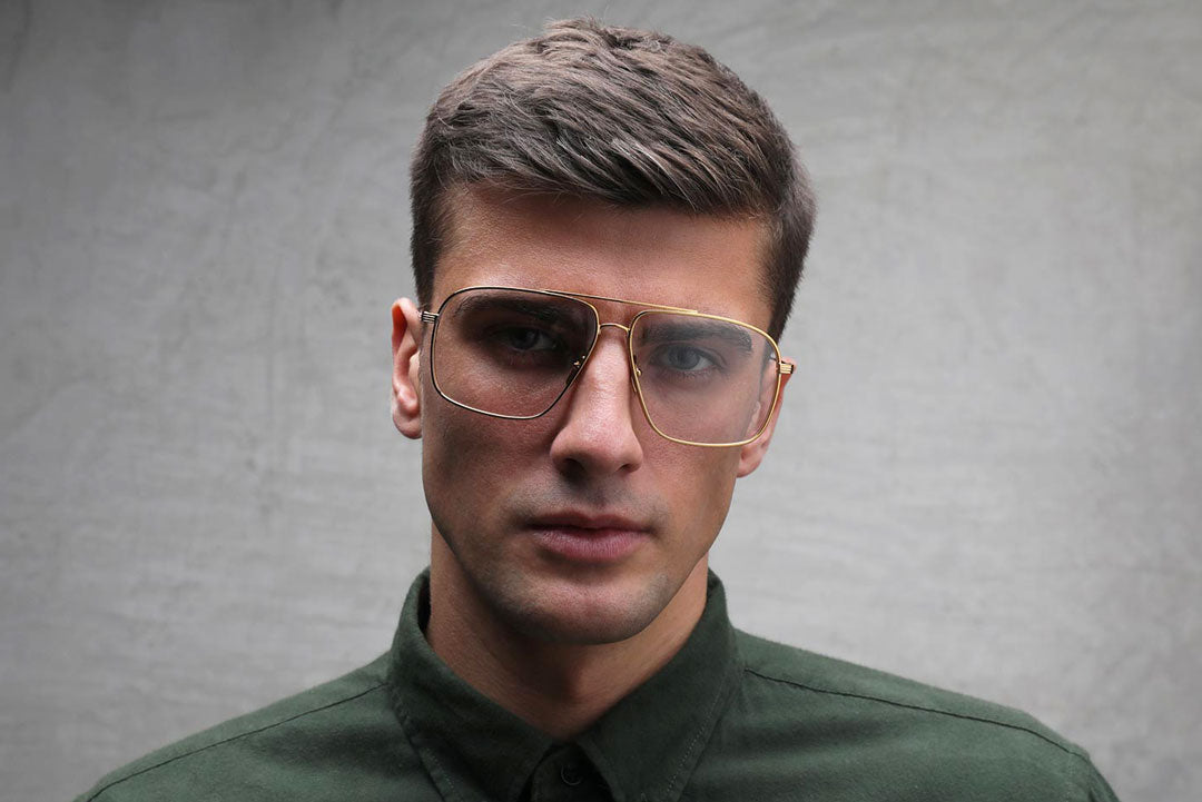 Man wearing large gold Aviator spectacles and green shirt
