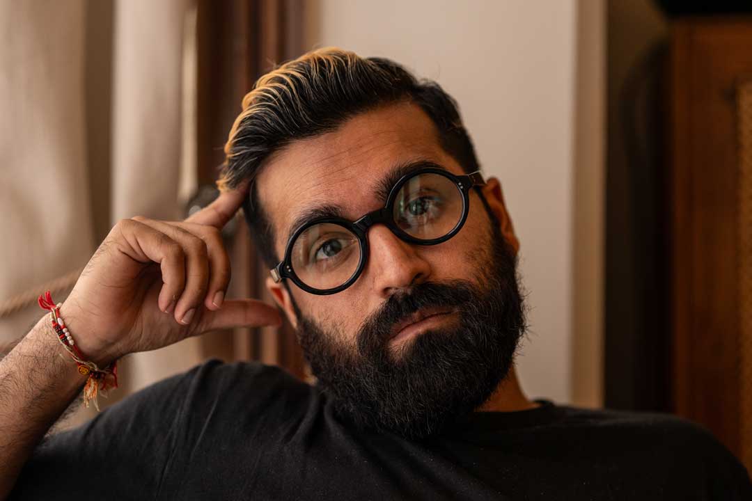 Man wearing round black eyeglasses frame resting his head on his hand