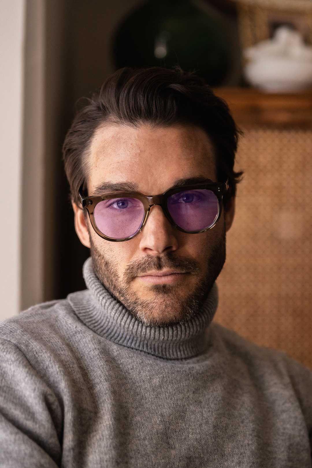 Man wearing thick frame eyeglasses with purple tinted lenses