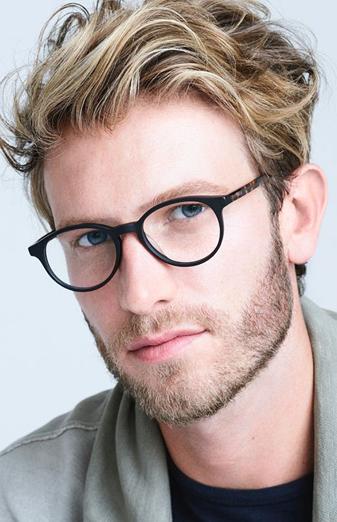 Man with dyed blonde hair looking through black circle eyeglasses