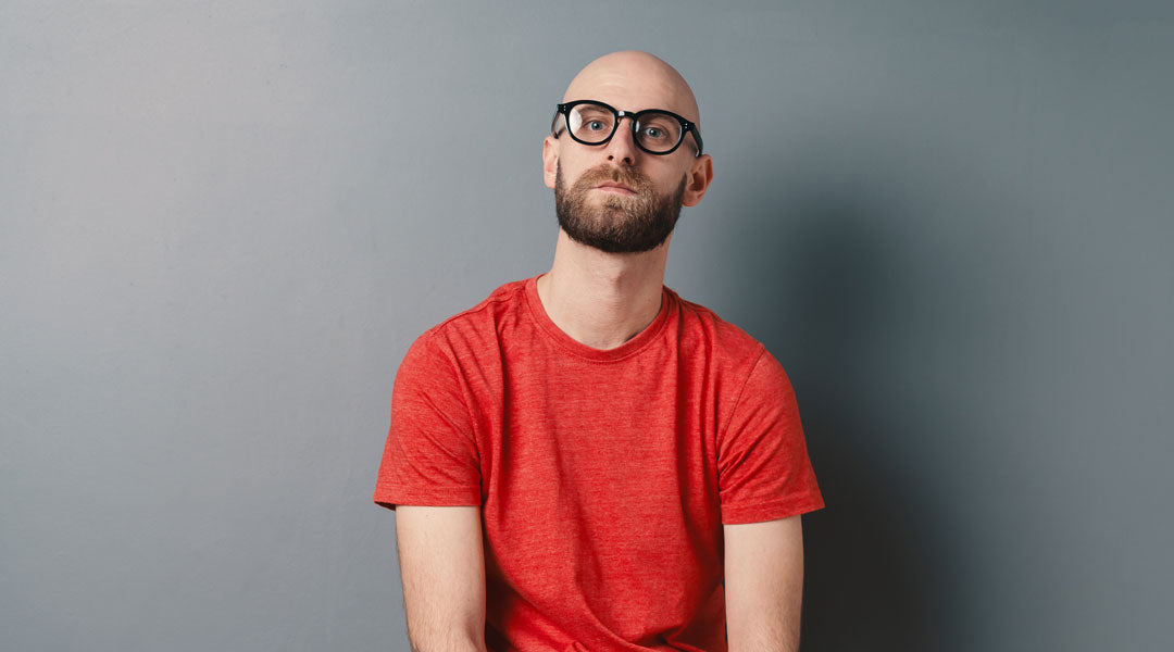 Man with no hair wearing thick black glasses and red T shirt