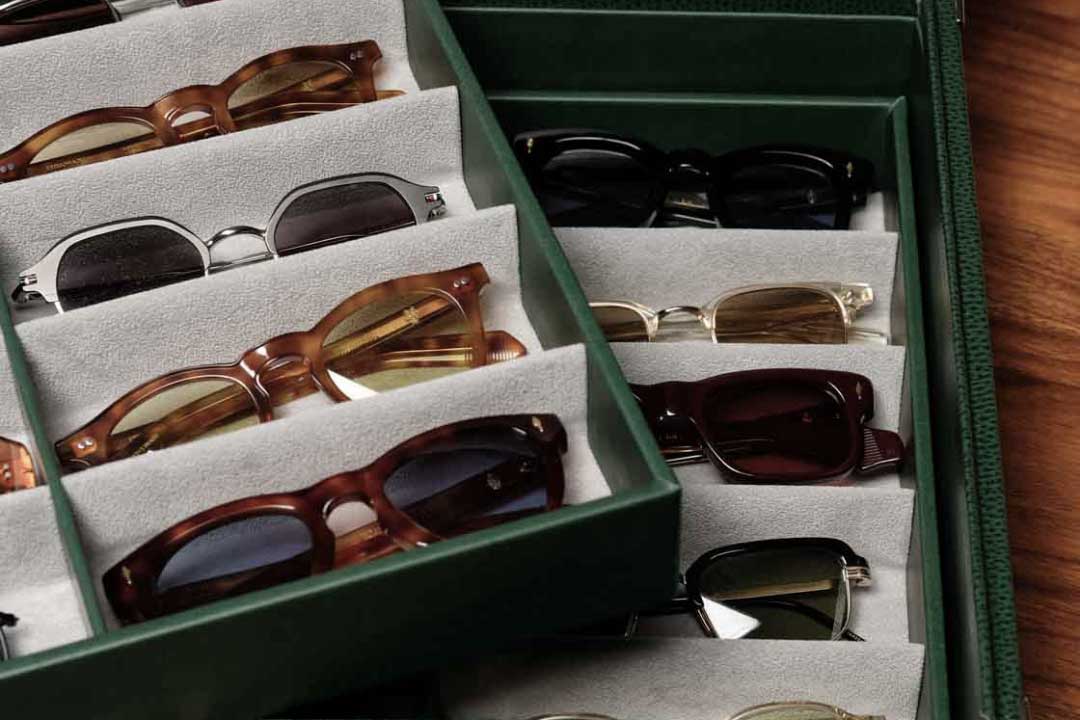 Multiple sunglasses frames inside green leather storage box