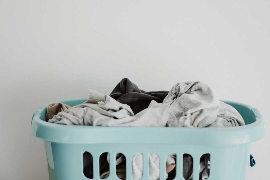 Pale blue washing basket filled with laundry and cleaning cloths