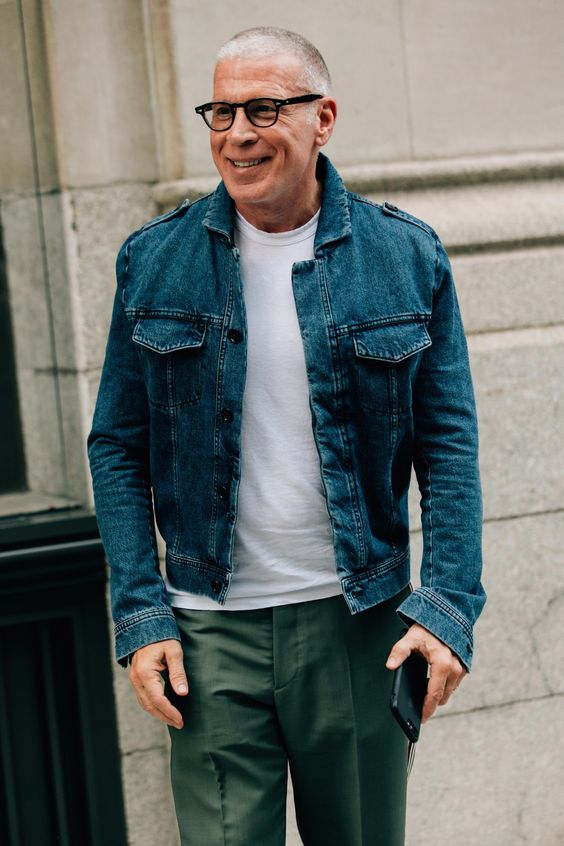 Partially bald man wearing thick black glasses and denim shirt