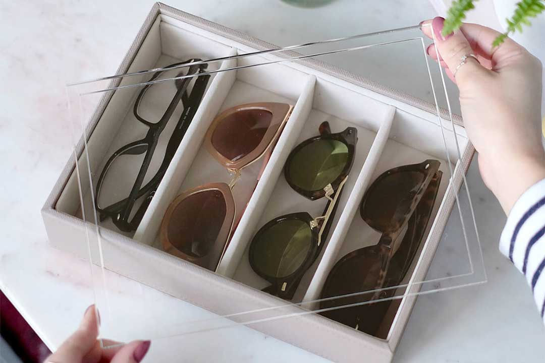 Person placing clear lid over sunglasses inside a white storage box