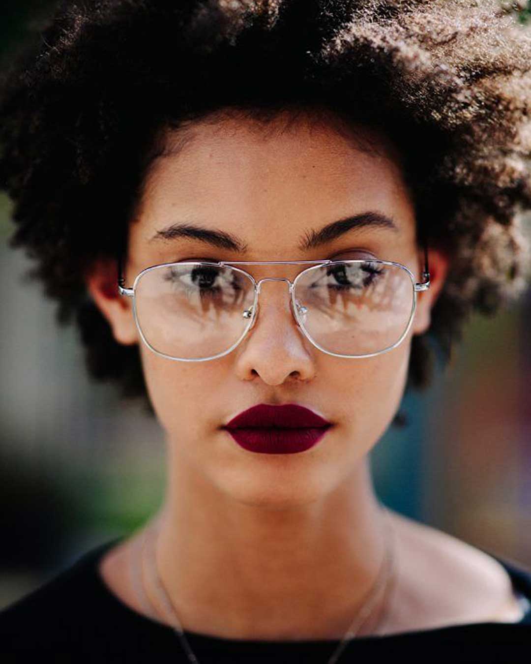 Portrait of black woman with large afro hair wearing silver Aviator spectacle frame