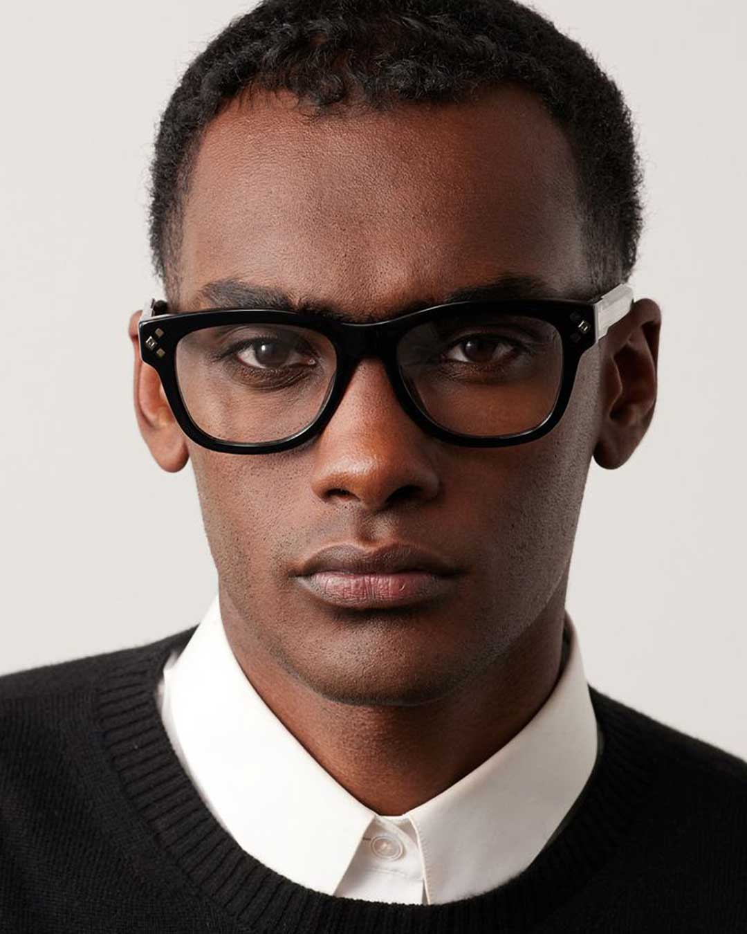 Portrait of man wearing thick black spectacle frame and black cardigan