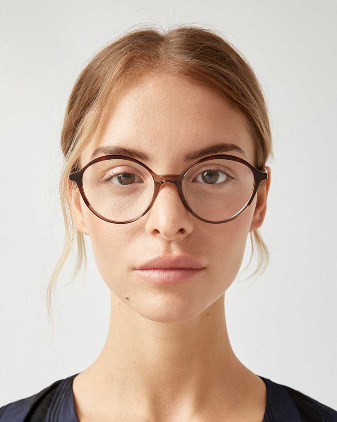 Portrait of young lady wearing transparent brown eyeglasses and blue blouse