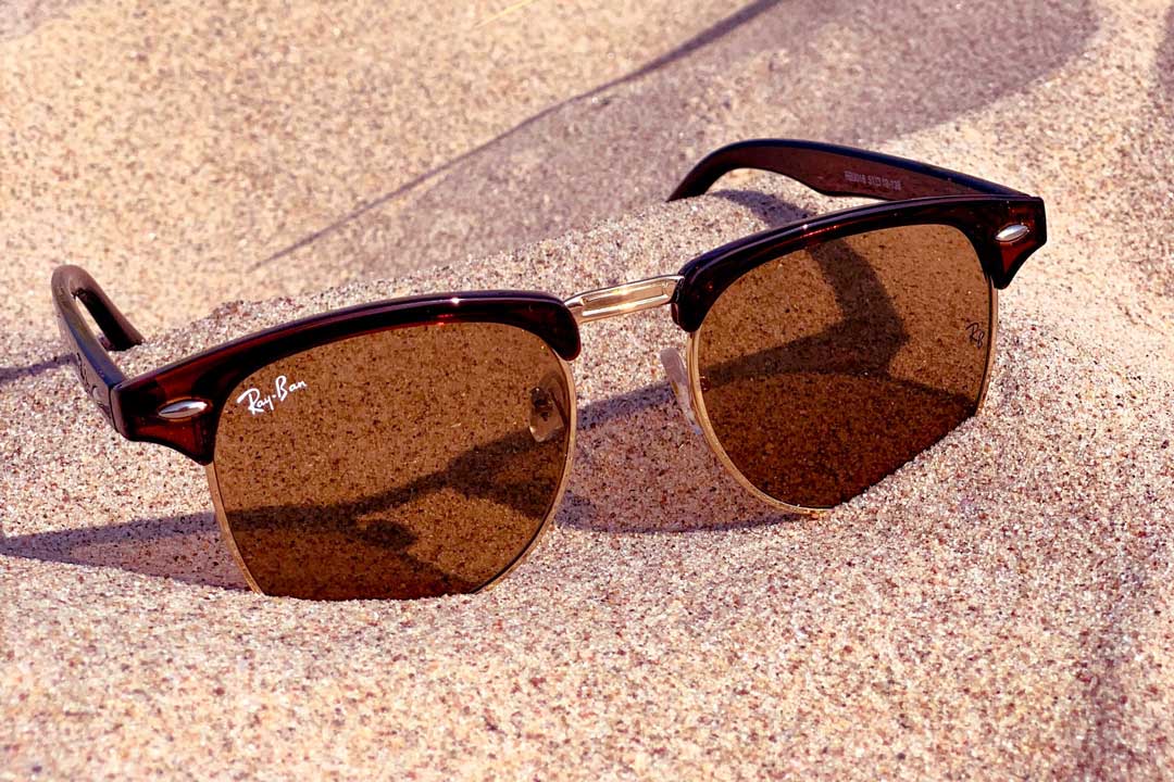 RayBan Clubmaster sunglasses frame on sandy beach