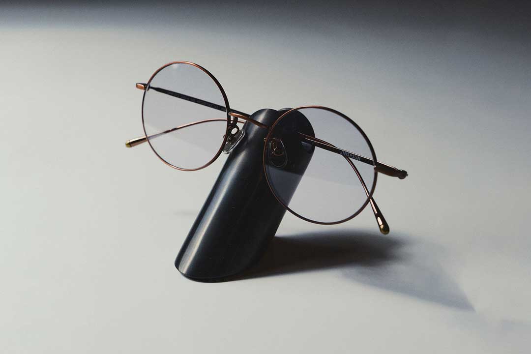 Round wire spectacles on black eyeglass holder