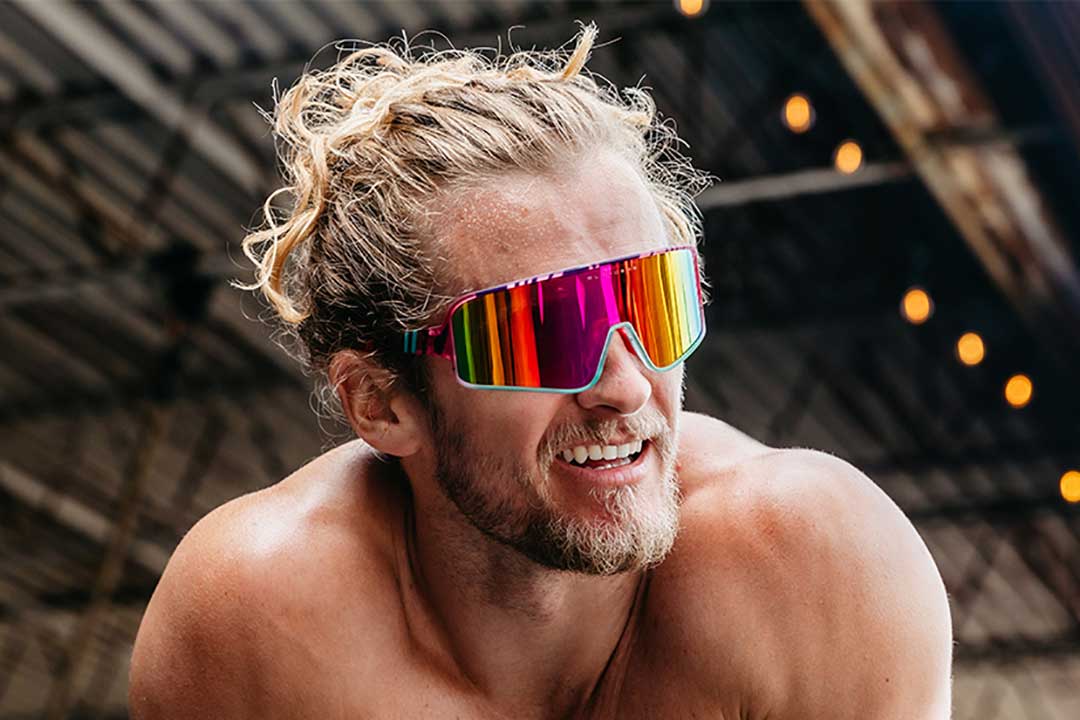 Shirtless man wearing 80s style visor sunglasses with mirrored lens