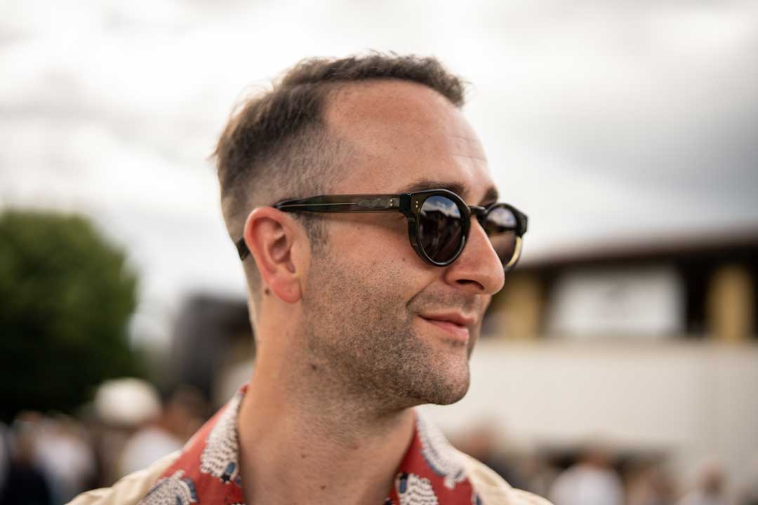Side view of a man wearing thick round sunglasses outside on sunny day