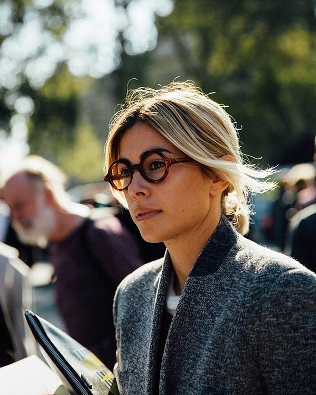 Side view of blonde lady wearing thick round Havana eyeglasses and wool coat
