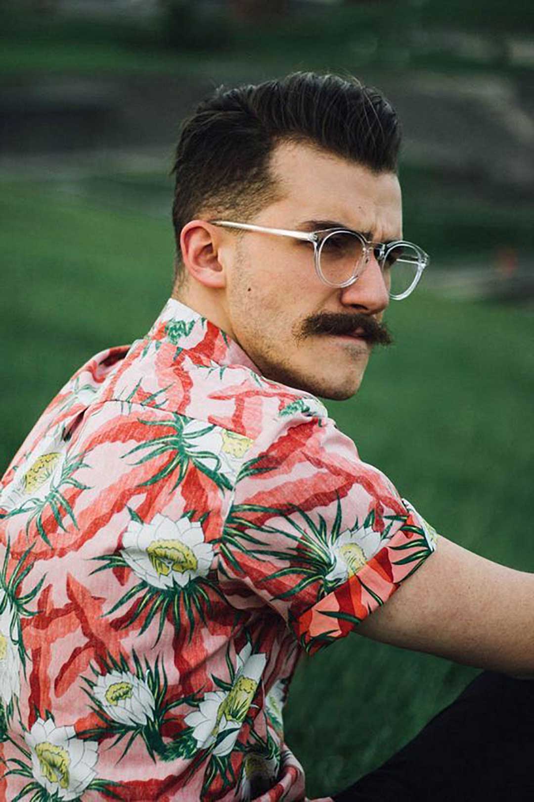 Side view of hipster man with moustache and round clear glasses wearing floral shirt