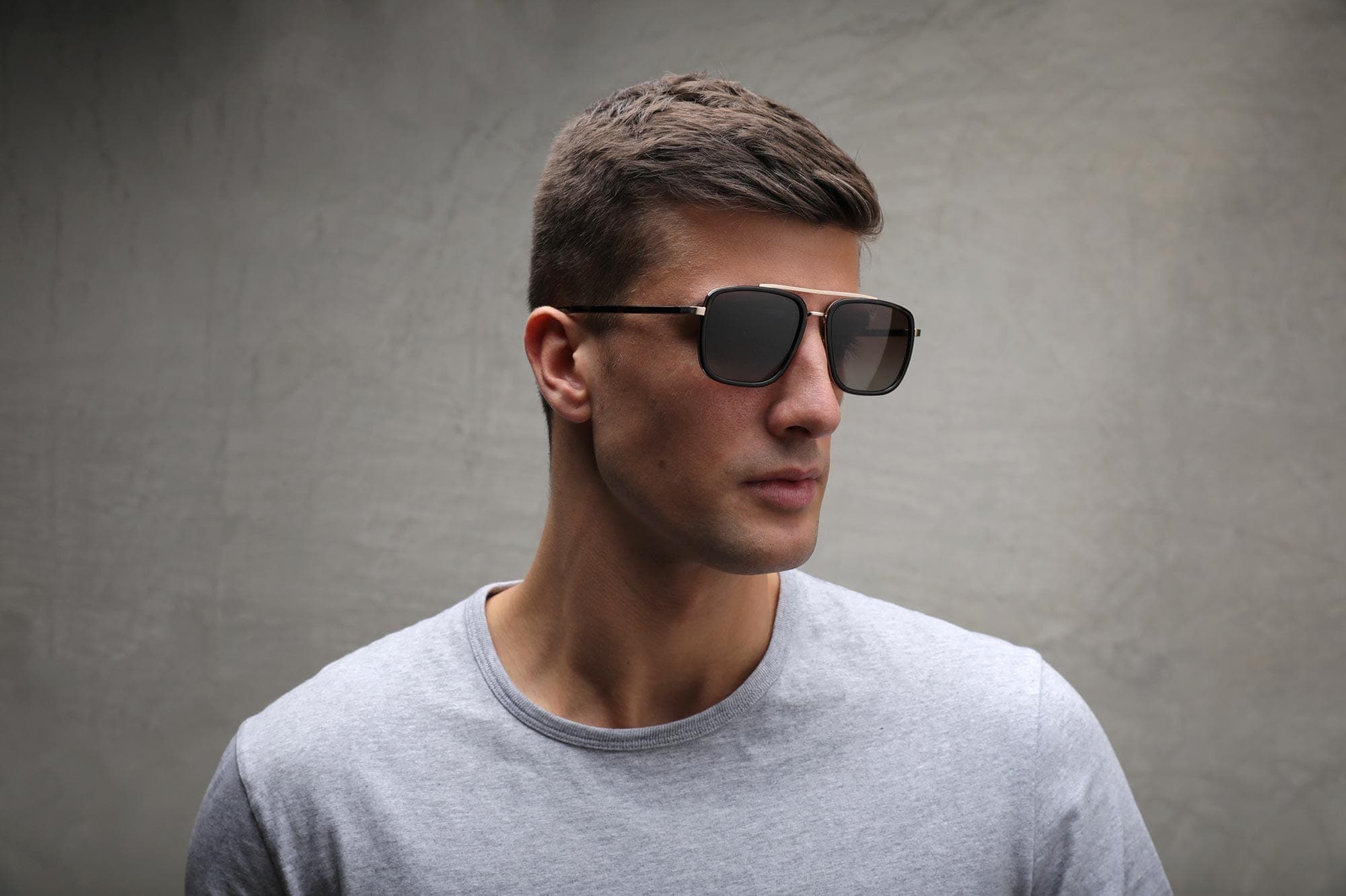 Side view of man wearing silver and black Aviator sunglasses frame with gradient brown lenses