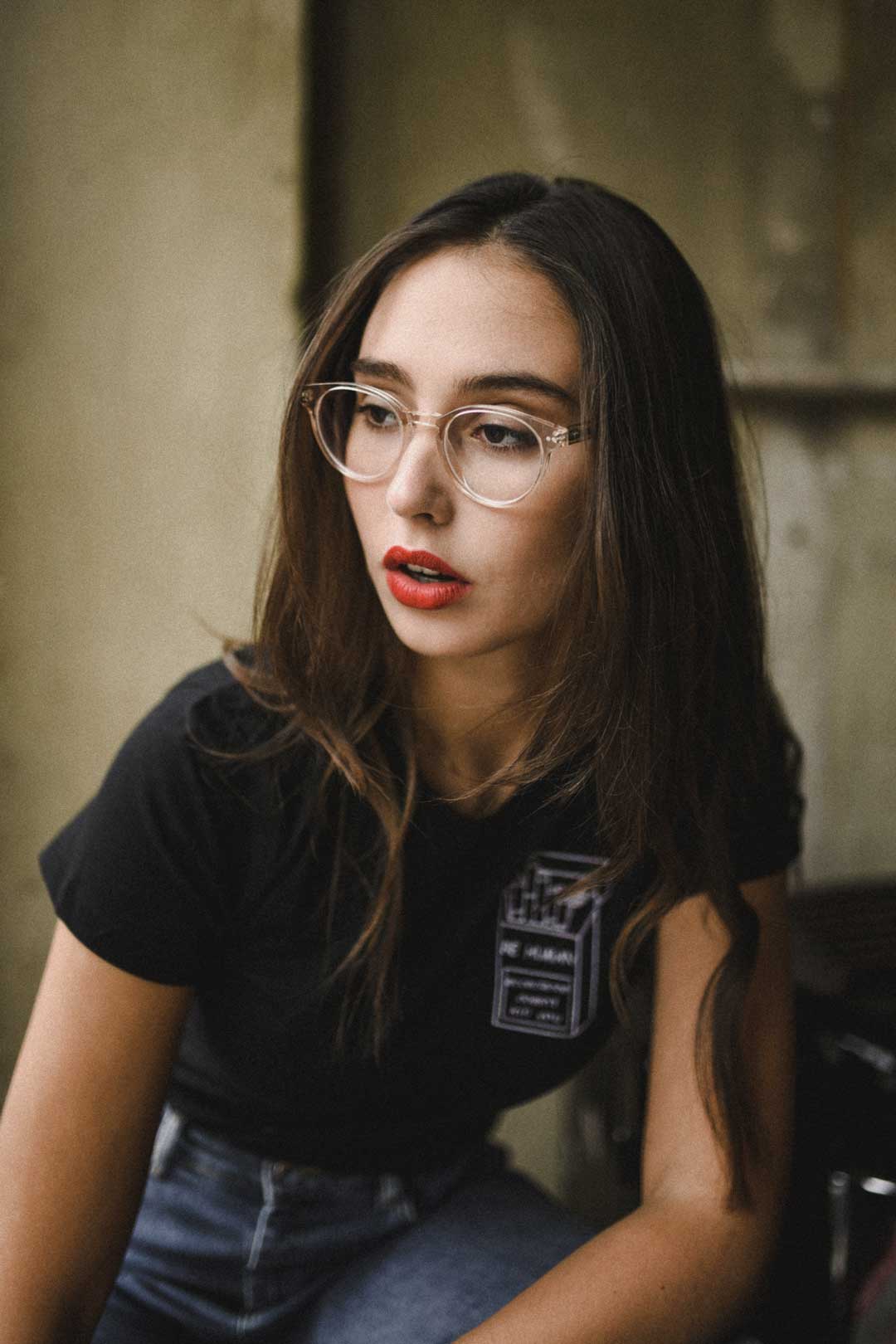 Side view of young brunette lady wearing clear frame eyeglasses
