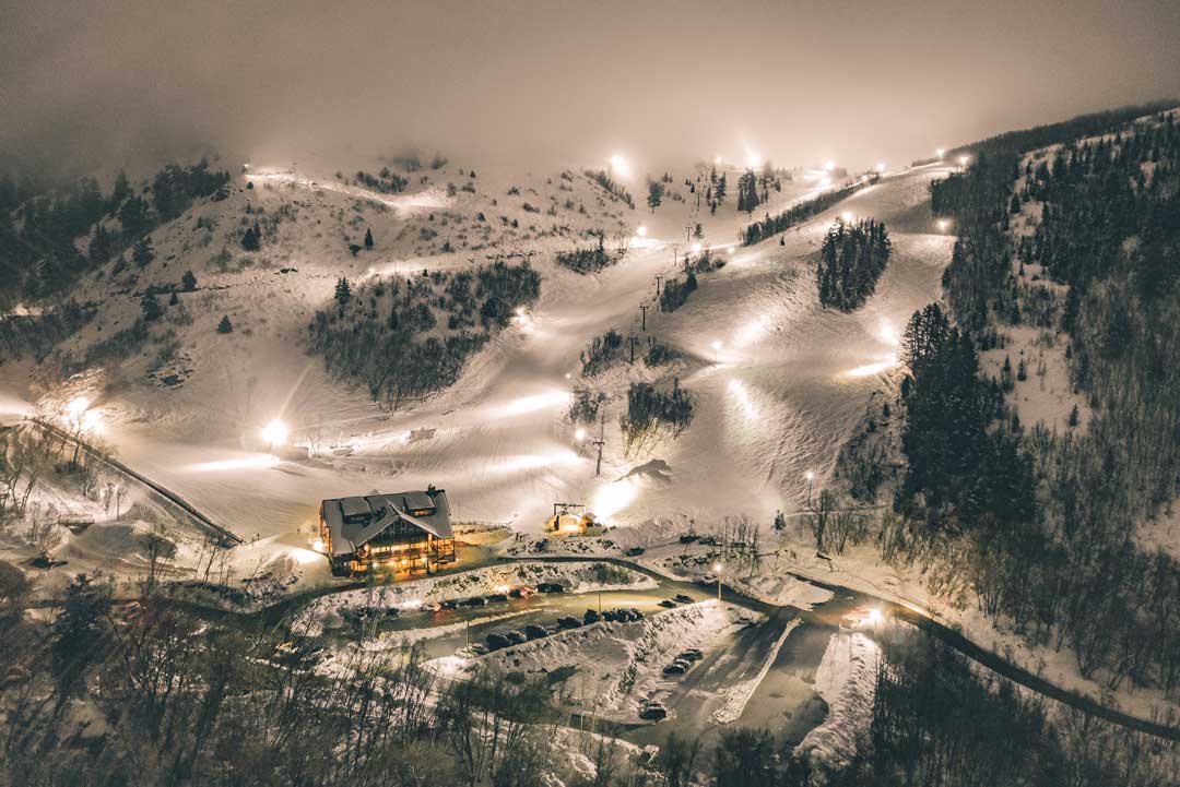 Ski mountain at night with slopes lit by large floodlights