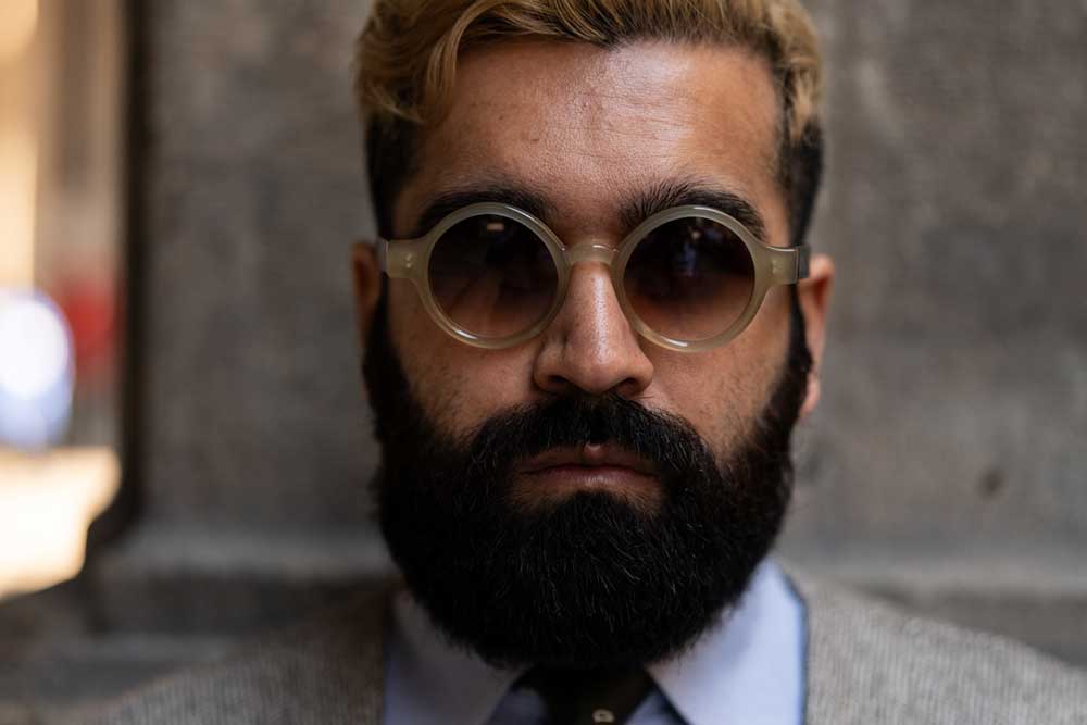 Smartly dressed man in suit and tie wearing round sunglasses frame