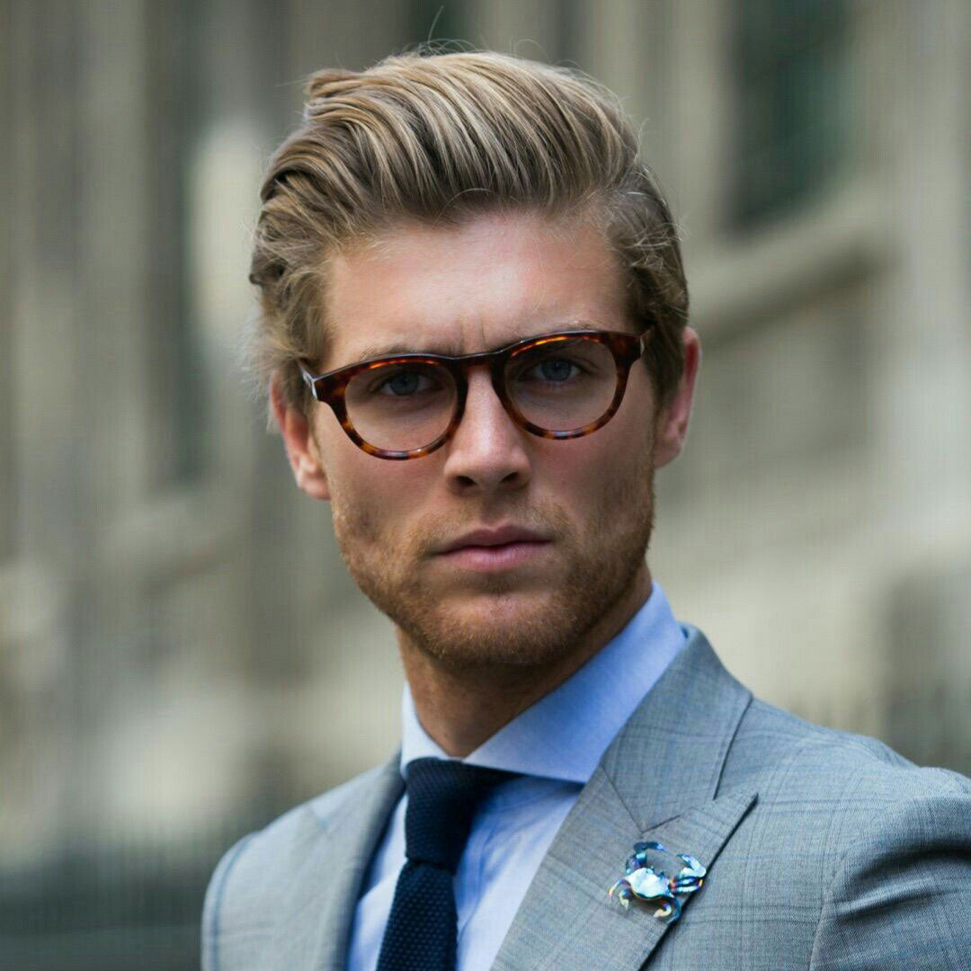 Street view of blonde man in suit and tortoise wayfarer eyeglasses