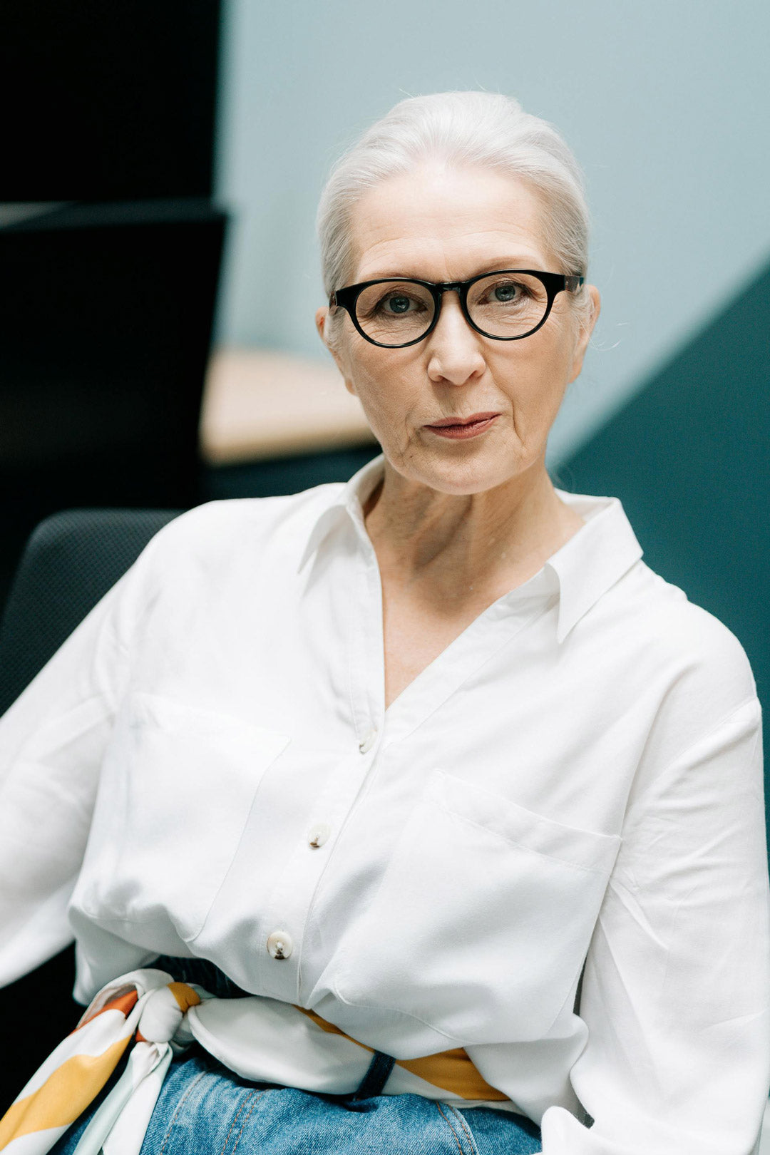 Stylish looking mature woman wearing thick black spectacle frame and white blouse