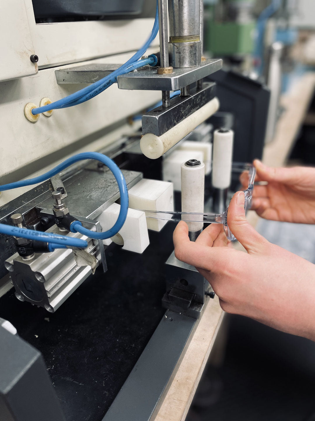 Sunglasses being hand inserted into temple bending machine