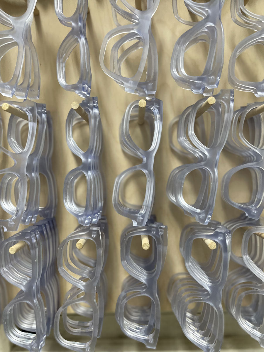 Sunglasses frame fronts hanging on a peg board inside factory workshop