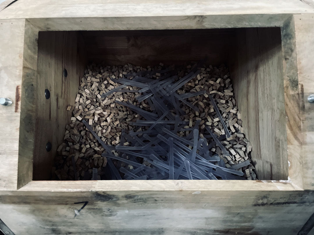 Sunglasses temples inside octagonal wooden chamber filled with beech polishing media