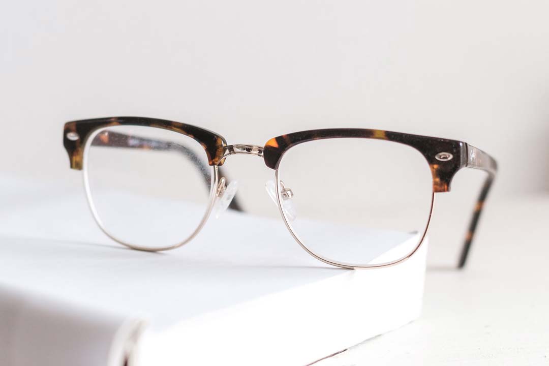 Tortoise shell browline glasses frame resting on a book