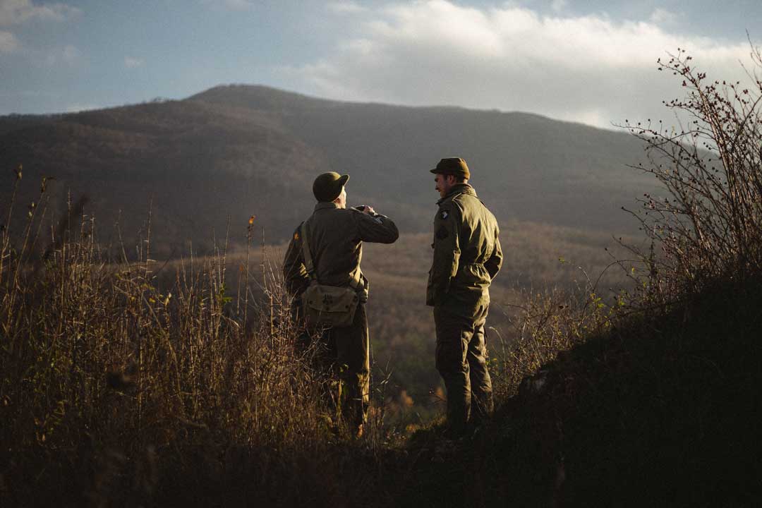 Two men outside on bright sunny day wearing hunting clothes