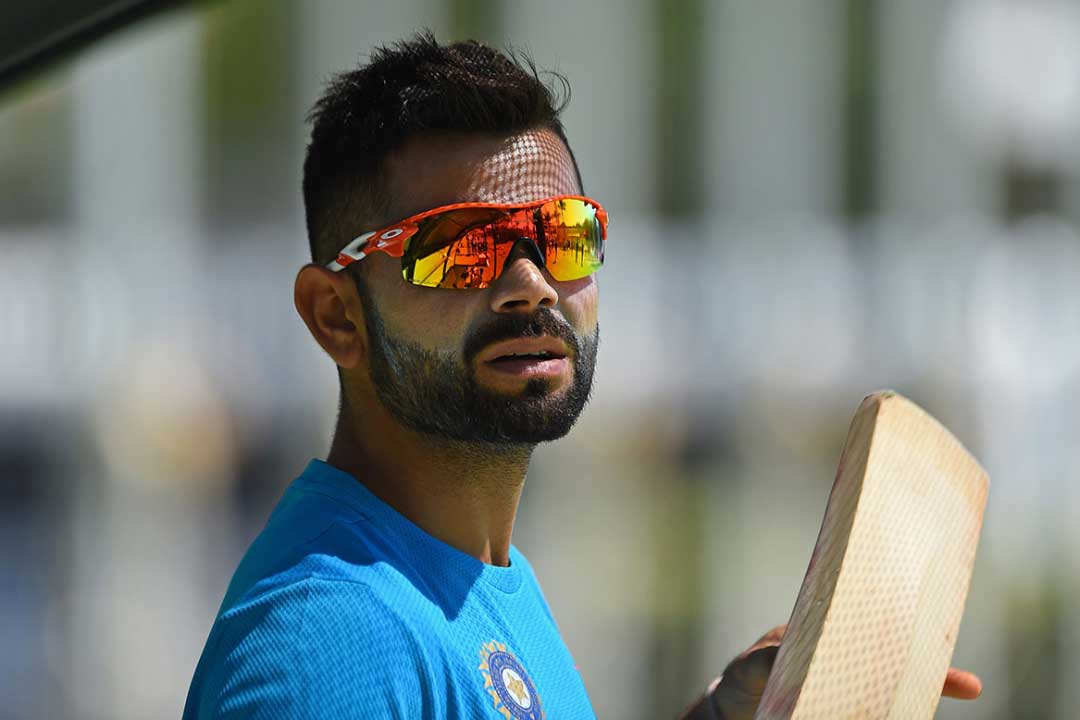 Virat Kohli wearing bright orange cricket sunglasses frame with gold mirror lenses