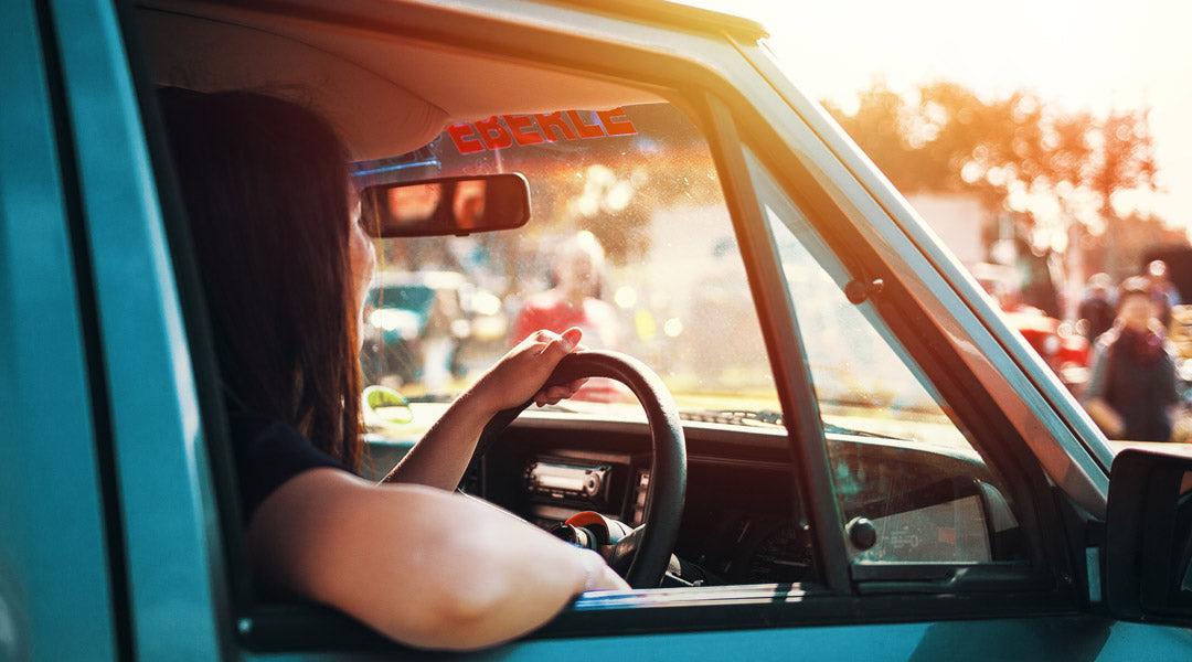 Woman driving blue car at sunset in a campsite