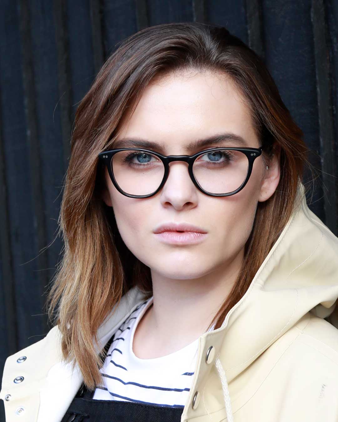 Woman wearing cream raincoat and black cat eye glasses frame