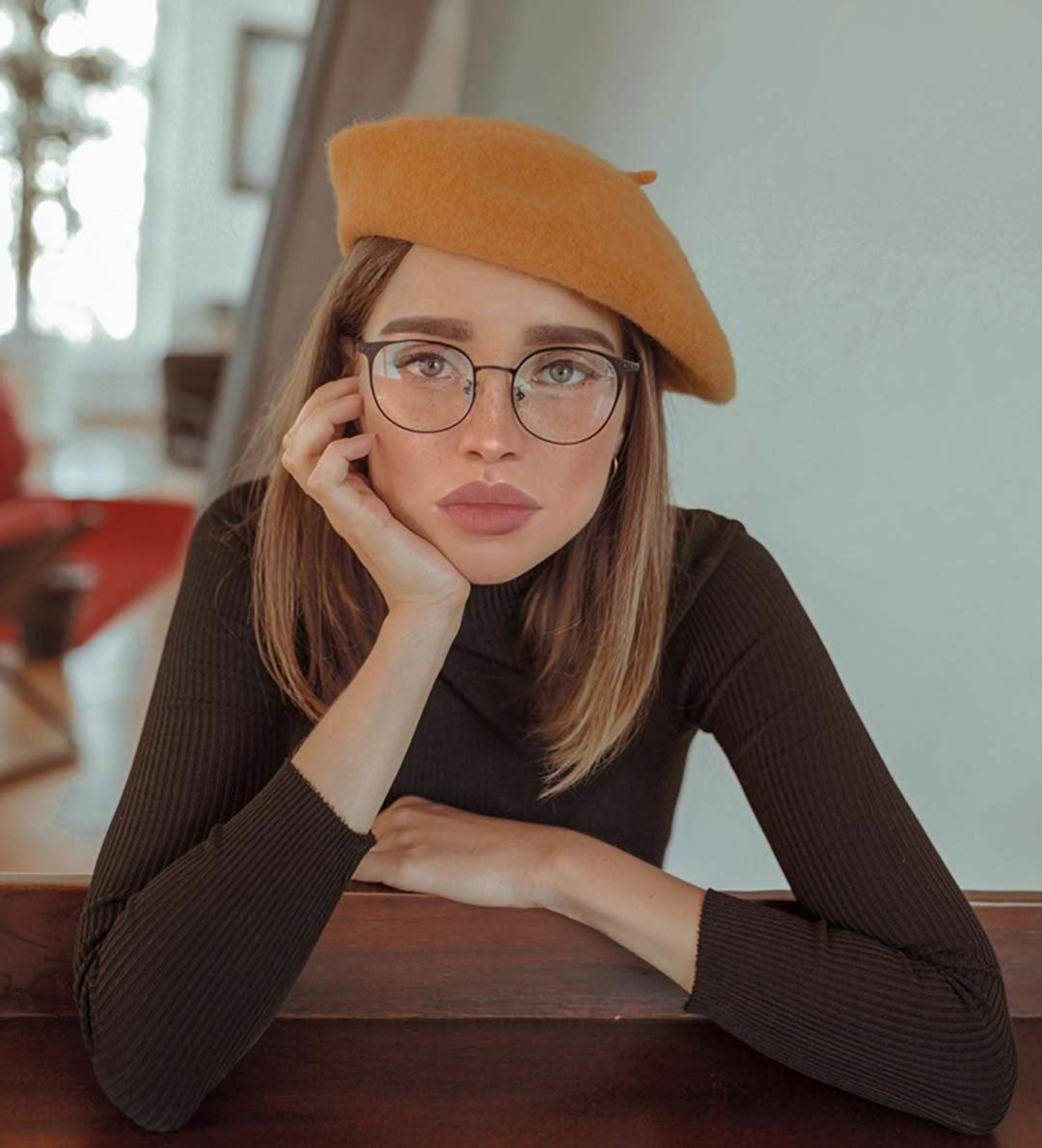 https://cdn.shopify.com/s/files/1/1045/8368/files/Woman-with-orange-beret-and-thin-eyeglasses-resting-her-head-in-one-hand.jpg?v=1643111097