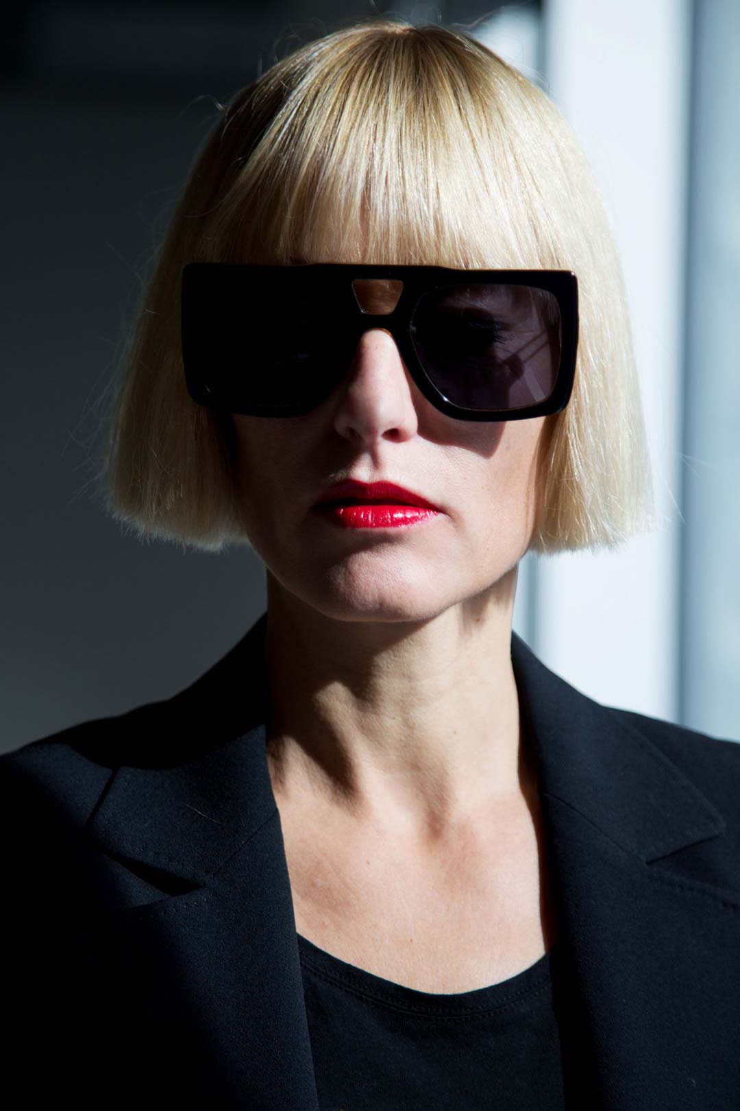 Woman with peroxide white blonde hair wearing square black sunglasses