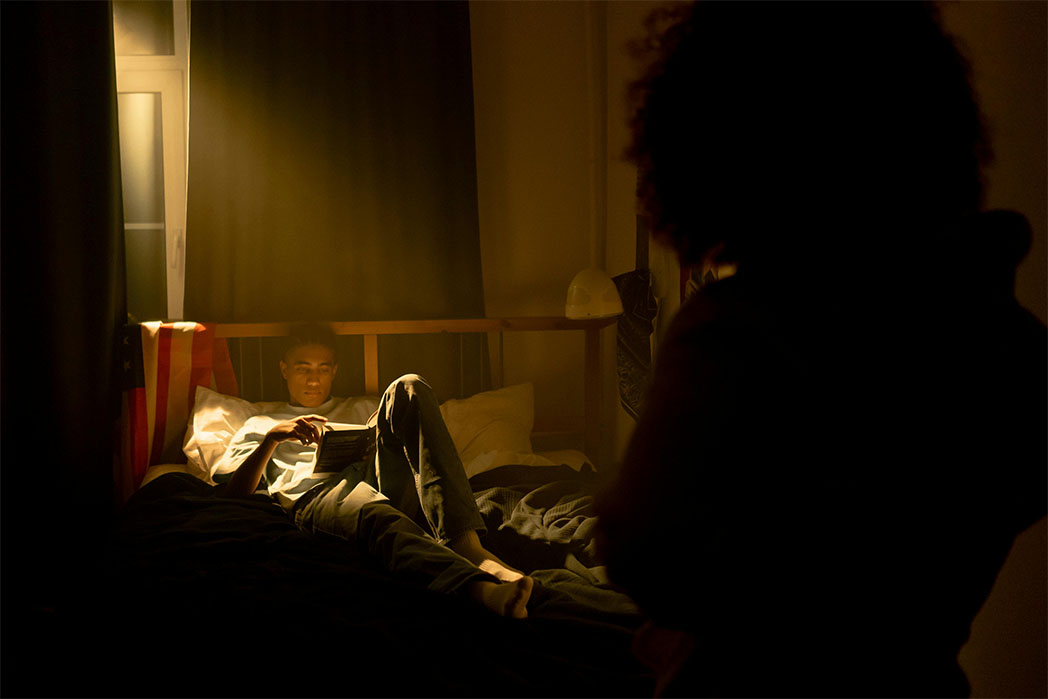 Young Man Reading in darkened room with woman looking over