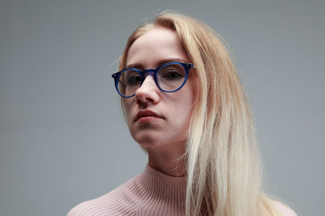 Young blonde female in pink top and round blue spectacles