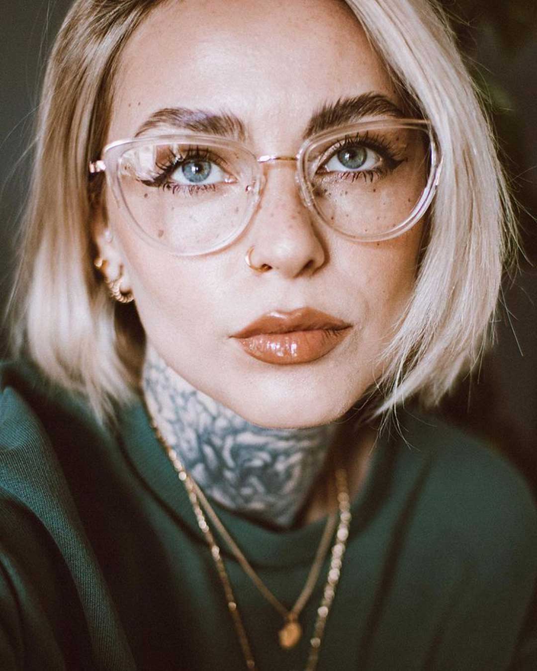 Young blonde woman wearing clear frame cat eye spectacles and green jumper
