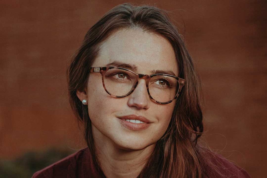 Young woman wearing tortoise spectacles looking away from viewer