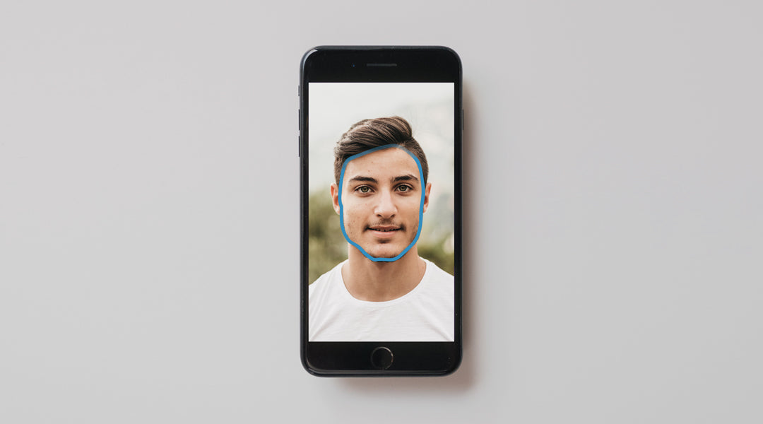 iPhone on grey table with photo of a man on screen with a trace outline around his face